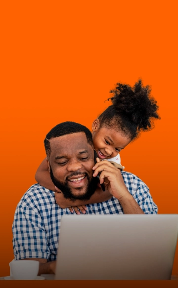 Criança abraçando adulto enquanto ele fala no celular e usa o computador | Crédito pessoal e consignado itau
