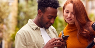 Foto de um casal de homem e mulher olhando o celular